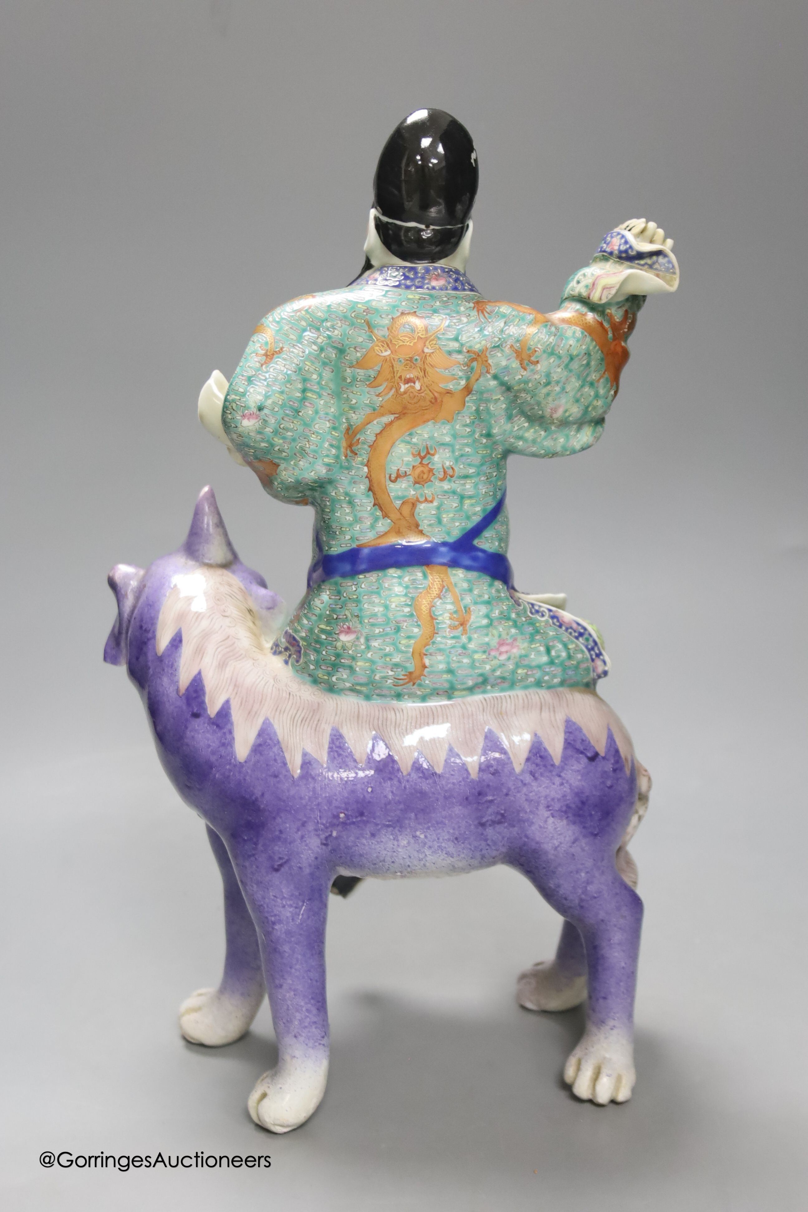 A Chinese enamelled porcelain figure group of an immortal on a mythical beast, Republic period, height 33cm